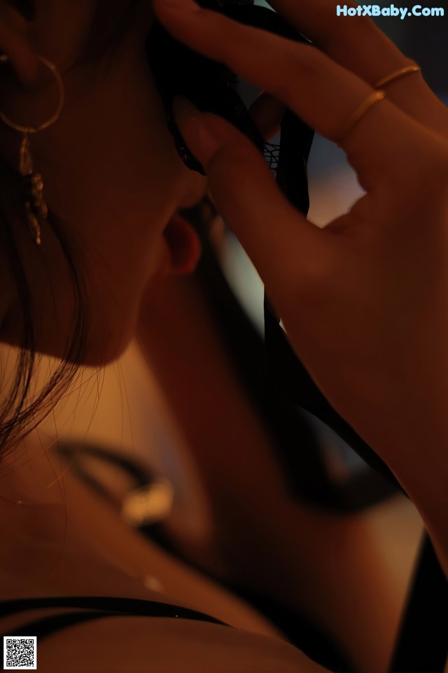 A woman in a black dress holding a cell phone to her ear.