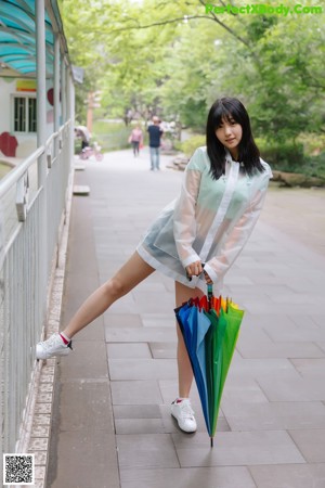A woman sitting on a bench holding an umbrella.