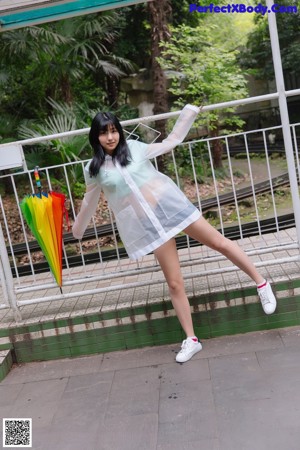 A woman standing on a bridge holding an umbrella.