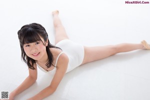 A woman in a white leotard laying on the floor.