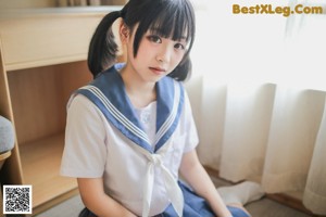 A woman in a school uniform is sitting on a couch.