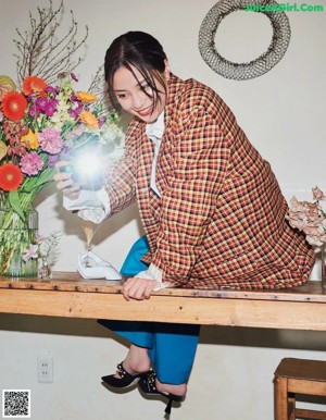 A woman sitting at a table with chopsticks in her hand.