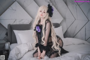 A woman in lingerie laying on a bed with a flower in her hair.