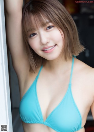 A woman in a blue bikini sitting on a chair.