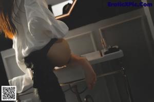 A woman in a white shirt and black panties holding a lipstick.