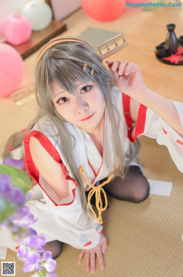 A woman in a white and red kimono sitting on the floor.