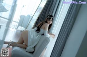 A woman sitting on a white couch in front of a mirror.