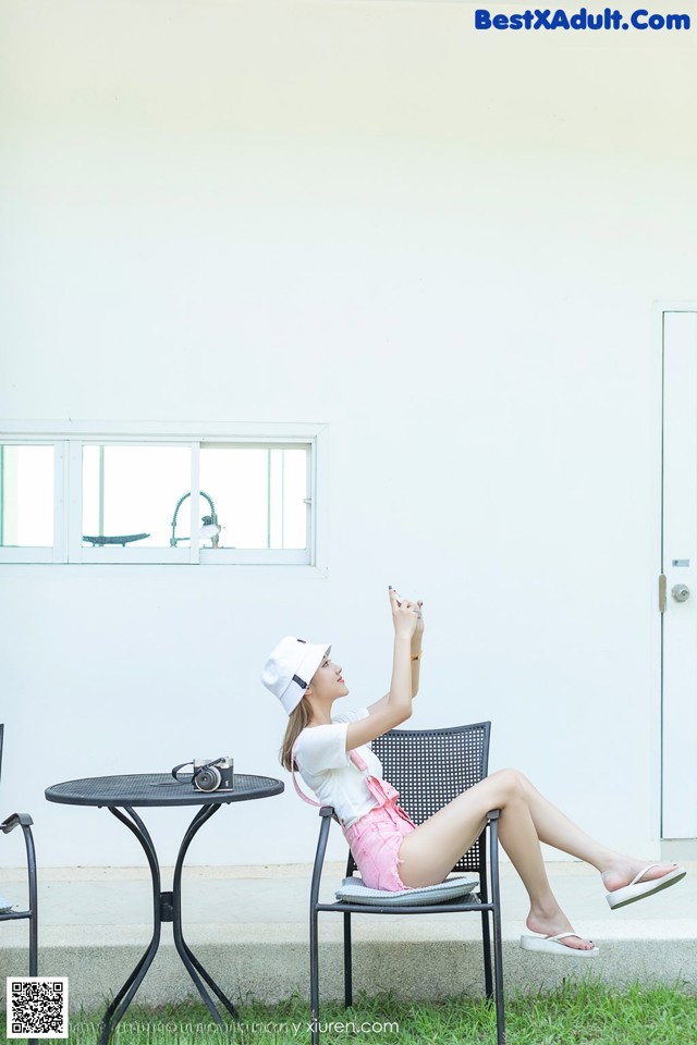 A woman sitting on a chair in front of a white wall.