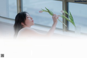 A woman in a white dress holding a white tulip.