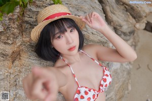 A woman in a bikini and a straw hat posing for a picture.