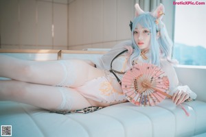 A woman with blue hair sitting on a white couch.