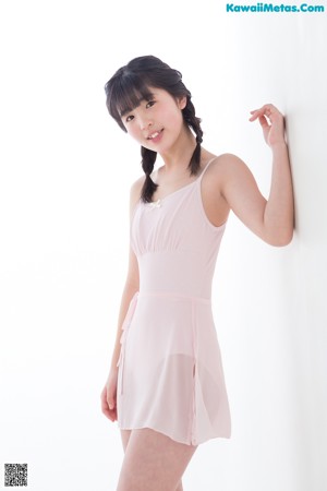 A young girl in a pink leotard is posing for a picture.