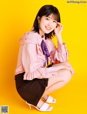 A woman in a pink shirt and purple tie posing for a magazine.