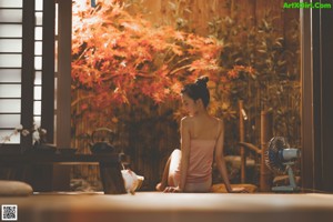 A woman standing in front of a window looking out the window.