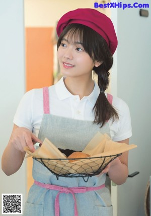 A woman in a pink hat and apron holding a white bag.
