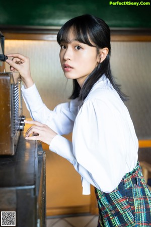 A woman in a yellow sweater sitting on a window sill.