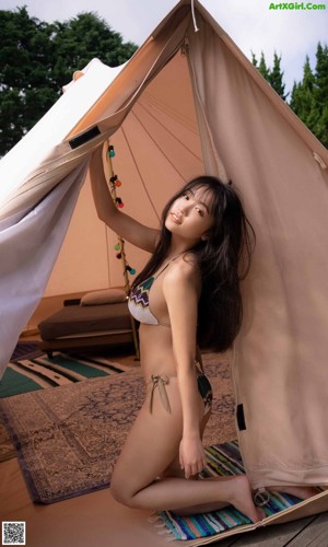 A woman in a bikini laying in a hammock.