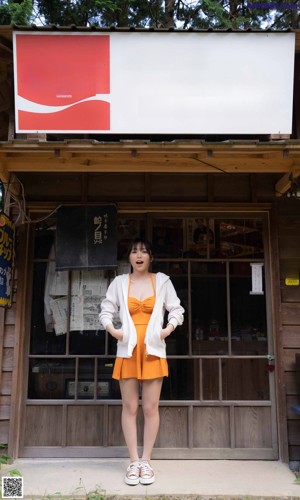 A woman in an orange dress standing in front of a door.