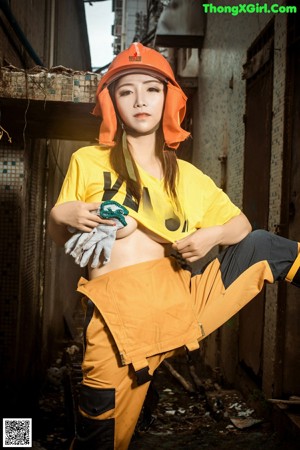 A woman in a yellow shirt and orange hard hat posing for a picture.