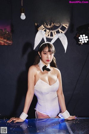 A woman in a white bodysuit posing for a picture.