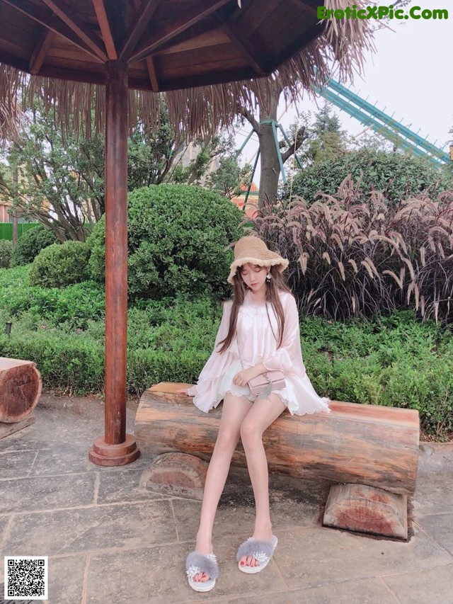 A woman sitting on a wooden bench in a park.