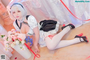 A woman in a maid outfit sitting on the floor.