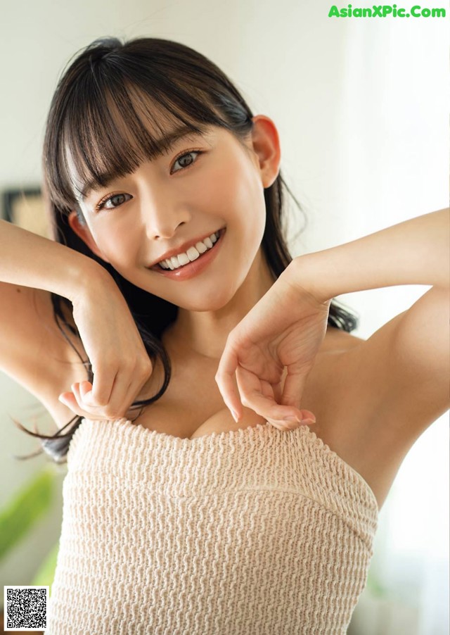 A woman in a beige tank top posing for a picture.