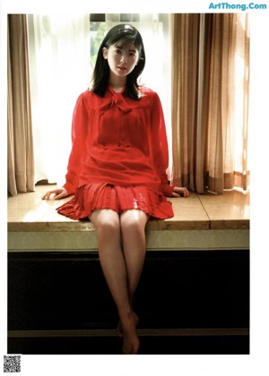 A woman in a red blouse poses for a picture.