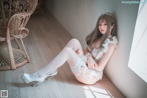 A woman sitting in a wicker chair wearing white lingerie.