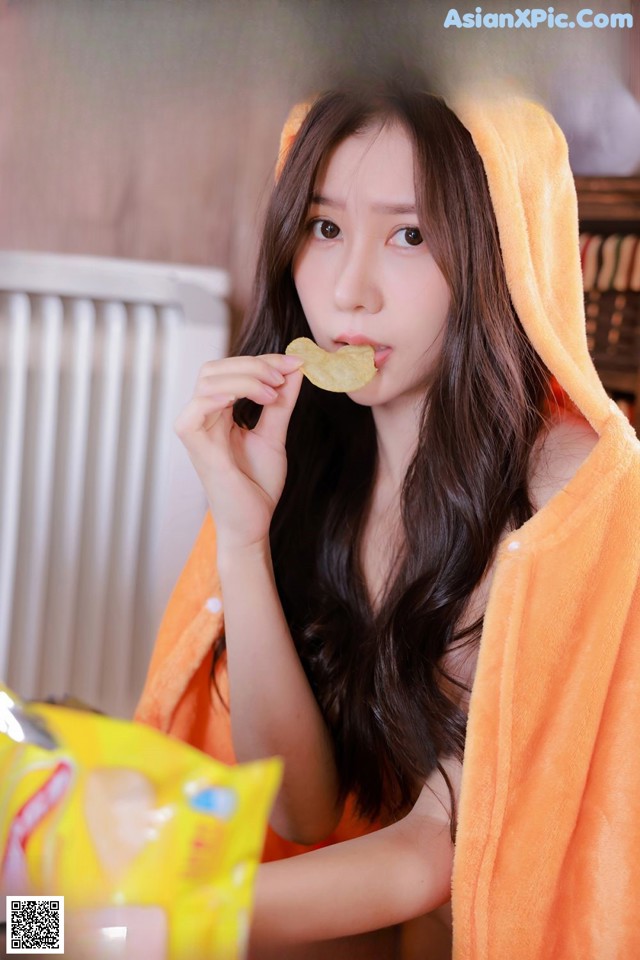 A woman in a towel eating a piece of food.