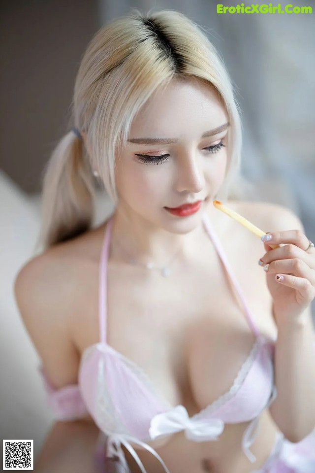 A woman in a pink lingerie holding a toothbrush.