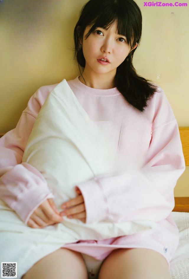 A woman sitting on a bed holding a pillow.