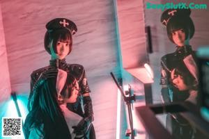 A couple of women dressed in latex sitting next to each other.