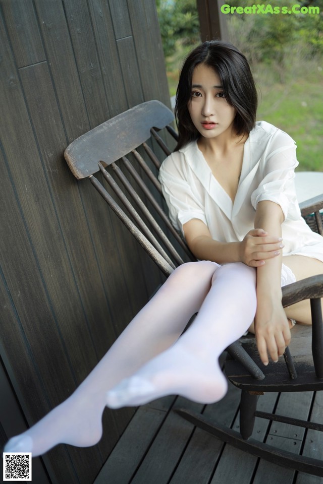 A woman sitting on a rocking chair wearing white stockings.