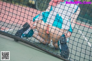A woman with pink hair sitting on a tennis court.