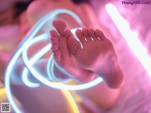 A woman laying on a bed covered in neon lights.