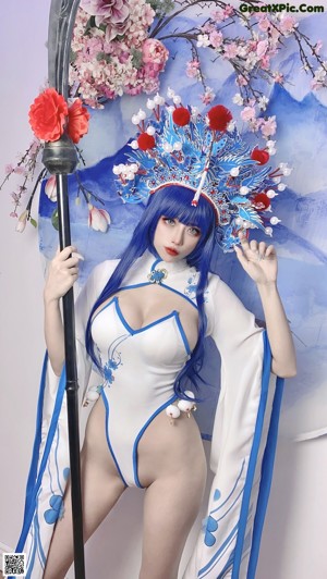 A woman with blue hair sitting on a white chair.