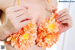 A woman in an orange bikini with flowers around her neck.